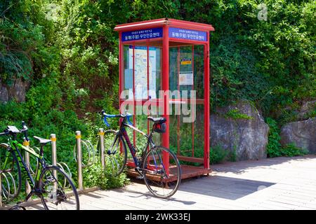 Donghae City, Südkorea - 28. Juli 2019: Fahrräder ruhen neben dem einzigartigen Chuam Chotdaebawi Certification Center, gekennzeichnet durch ein markantes rotes Telefon Stockfoto