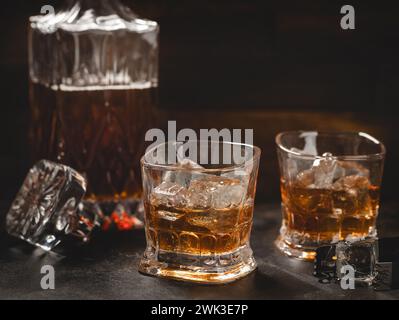 Zwei Gläser Whiskey mit Eis und Dekanter auf hölzernem Hintergrund für Kopierraum Stockfoto