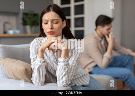 Besorgte junge Frau mit verärgertem Mann im Hintergrund Stockfoto