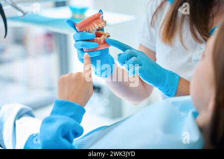 Frau in Schutzhandschuhen lehrt die Mundhygiene von Kindern Stockfoto