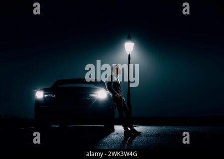 Mann lehnt sich nachts gegen das Auto mit einem Leuchtenpfosten, USA Stockfoto