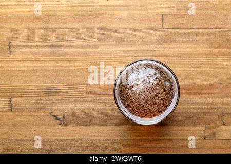 Blick von oben auf ein frisch gegossenes Craft-Bier in einem Glas auf einem warmen Holztisch Stockfoto