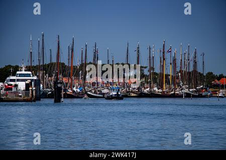 Eine Flotte von Booten, die an einem Dock vorbeischwimmen, umgeben von anderen Schiffen Stockfoto