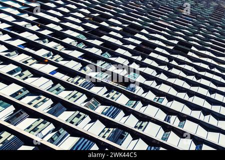 Eine Wand aus vielen Fenstern und Reflexionen, die auf das Äußere der zeitgenössischen Architektur blicken. Gefiltert in kühlen Tönen. Architektonische abstrakte Backgr Stockfoto