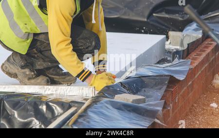 Installation einer Schaumpolystyrolplatte unter Betonboden zur Wärmedämmung des Hauses während der Bauarbeiten. Energie durch Isolieren des Hauses trennen Stockfoto