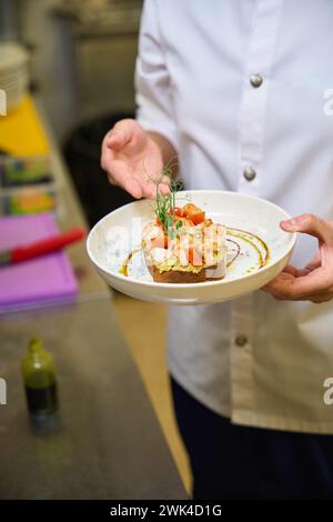 Der Koch präsentiert Toast mit Avocado und Garnelen Stockfoto