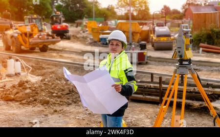 Weibliche Bauingenieurin, die mit Theodolit-Totalstationen-EDM-Geräten auf einer Baustelle im Freien arbeitet Stockfoto
