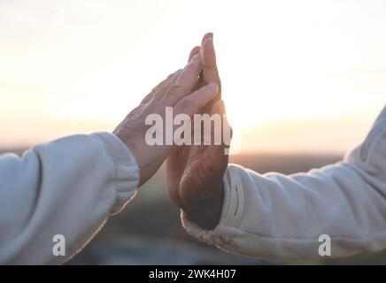 Hände eines weißen Mannes und eines schwarzen afroamerikanischen Mannes berühren sich bei Sonnenuntergang sanft und sanft. Konzept des Kampfes mit Rassismus und Freundschaft zwischen Stockfoto