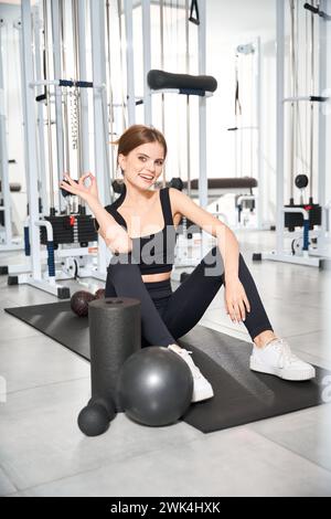 Schöne junge Frau sitzt auf einer Turnmatte Stockfoto