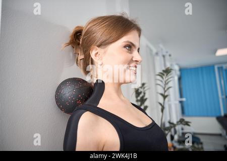 Schöne Frau führt Übungen an der Wand mit einem speziellen Gerät aus Stockfoto
