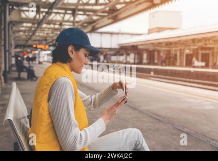 Junge Frau mit Pass und Fahrkarten, die am Bahnhof auf den Zug wartet und das Reisekonzept genießt Stockfoto