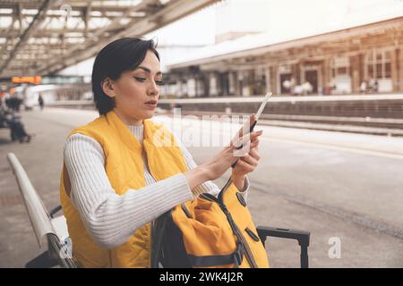 Junge Frau mit Pass und Fahrkarten, die am Bahnhof auf den Zug wartet und das Reisekonzept genießt Stockfoto