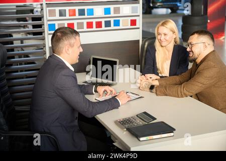 Drei Personen sitzen an einem Tisch in einem Autohaus Stockfoto