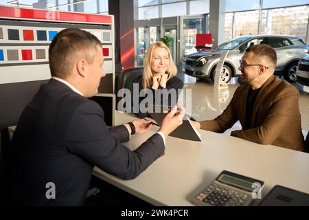 Drei Personen sitzen an einem Tisch in einem Händlerbetrieb Stockfoto