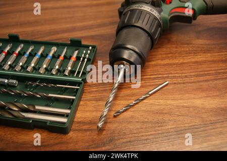 Neuer Bohrer- und Bohrersatz. Ein Bohrer und ein Satz Bohrer auf einem dunklen Holztisch. Stockfoto