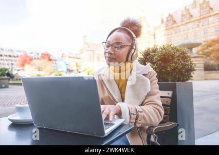 Afrikanische Frauenstudentin e Lern-Fernschulungskurs-Studium Arbeit im Café. Ethnische junge Frau, die sich ein Webinar über das Online-Bildungssystem mit Laptop ansieht. Stockfoto