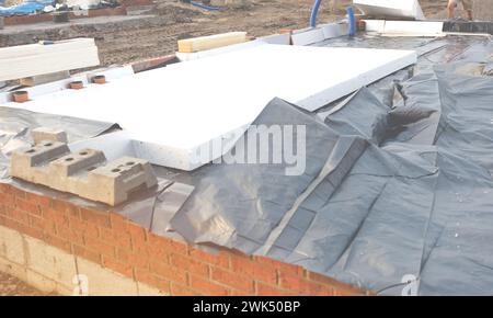 Baumeister legt Polystyrol-Dämmplatten auf Wasserabdichtungsmembran während des Bodenbaus. Energiesparkonzept Stockfoto