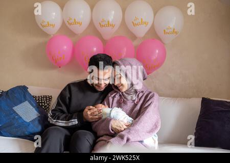 Arabische muslimische Paare halten ihre Neugeborenen-Feier im Wohnzimmer mit Ballons und Rosa ab Stockfoto