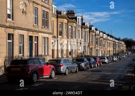 Eine Reihe von Autos, die außerhalb von Reihenhäusern im Gebiet von Inverleith in Edinburgh, Schottland, Großbritannien geparkt wurden. Stockfoto