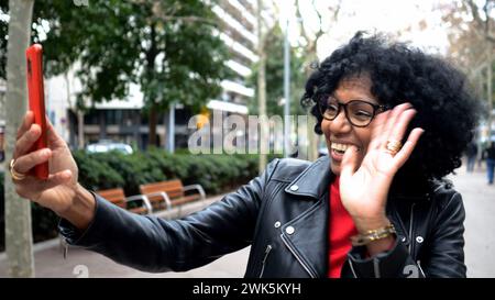 Afroamerikanerin mittleren Alters in einer Stadt, die mit einem Mobiltelefon in einer Stadt einen Videoanruf macht Stockfoto