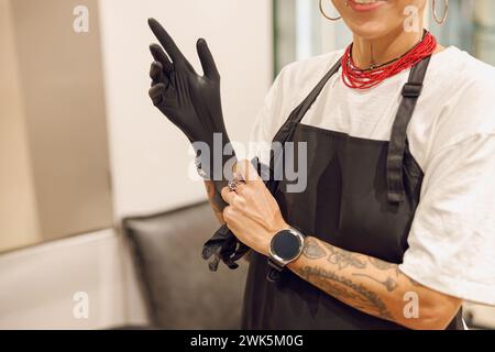 Nahaufnahme eines Friseurs, der Handschuhe anzieht, bevor er Haare im Schönheitssalon färbt Stockfoto