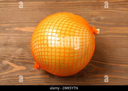 Frische Pomelo-Frucht im Netz auf hölzernem Hintergrund Stockfoto