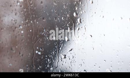 Makro von Wassertropfen auf Glas. Große Regentropfen schlagen während der Winterdusche auf das Fenster. Reine Regentropfen. Stockfoto