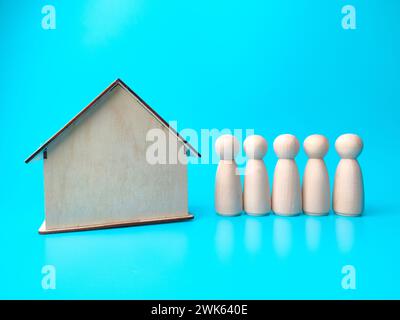 Holzfiguren und Holzhaus auf blauem Hintergrund. Immobilienkonzept. Stockfoto