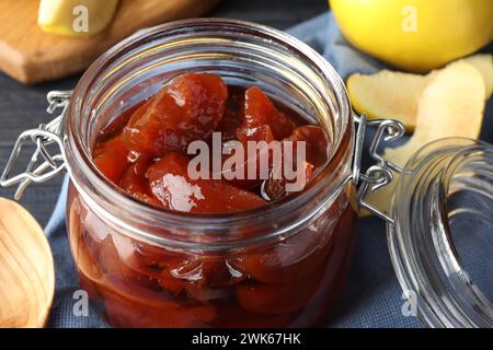 Quittenmarmelade im Glas und frisches rohes Obst auf dem Tisch, Nahaufnahme Stockfoto