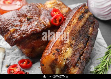 Gebackene Schweinebauchstücke serviert mit Rosmarin und Chili auf dem Tisch, Nahaufnahme Stockfoto