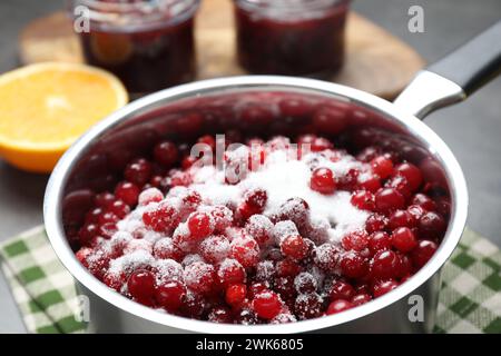 Preiselbeersauce herstellen. Frische Preiselbeeren mit Zucker in einem Topf auf dem Tisch, Nahaufnahme Stockfoto