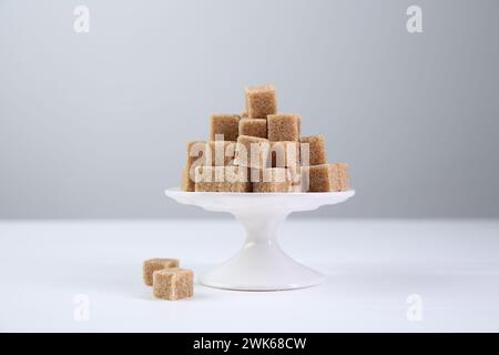 Braune Zuckerwürfel auf weißem Tisch vor hellem Hintergrund Stockfoto