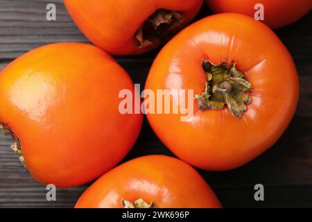 Köstliche reife Persimmons auf dunklem Holztisch, Blick von oben Stockfoto