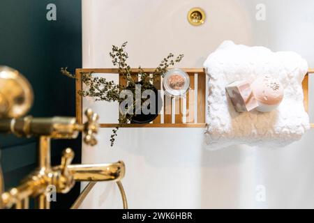 Komposition aus Messing-Duschhahn, Holzbadewanne mit Zimmerpflanze und einem Glas Himalaya-Salz, Inneneinrichtung für ein Badezimmer. Stockfoto