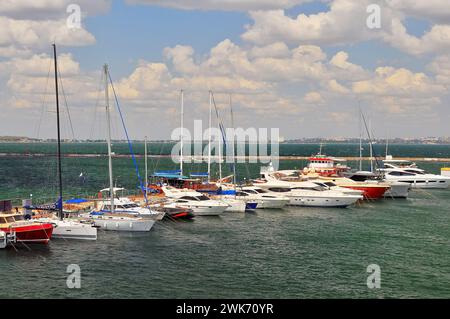 Odessa, Ukraine. 22. Juli 2021. Weiße Yachten liegen am Pier, das Meer ist smaragdgrün. In der Ferne sieht man den Wellenbrecher und die Stadt Stockfoto