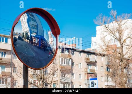 Runder Übersichtspiegel an einem Mast, um die Sicht auf die Straße zu verbessern, gefährliche Kreuzung. Sphärischer Spiegel auf einer Stadtstraße Stockfoto