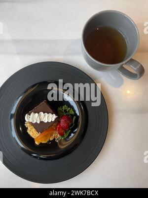 Blick von oben auf ein köstliches Schokoladenstück mit frischen Beeren und einer Tasse Tee Stockfoto