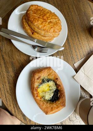 Blick von oben auf frisch gebackene köstliche Brötchen mit Käse und Spinat auf Tellern. Leckeres Frühstück Stockfoto