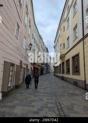 Die Menschenmassen schlendern auf einem alten Bürgersteig im historischen Stadtteil Linz, Österreich Stockfoto