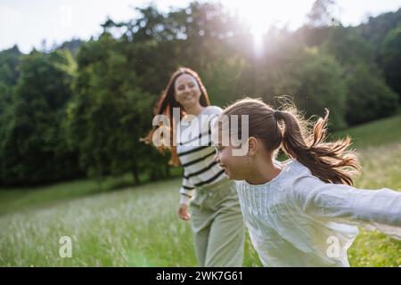 Schöne Mutter mit Tochter, die auf der Wiese spielt, rennt und Spaß hat. Muttertag und mütterliche Liebe. Stockfoto