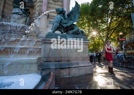 FRANKREICH / Ile de France / Paris / Junges Mädchen im kurzen roten Sommerrock spaziert am Brunnen in Place Saint Michel. Stockfoto