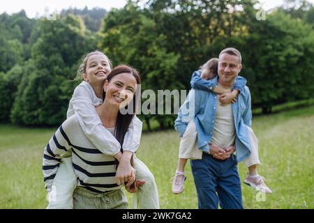 Porträt einer schönen Familie, Eltern, die zwei Töchter pfucken, Spaß in der Natur haben. Stockfoto