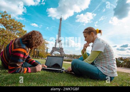 FRANKREICH / Ile de France / Paris / Junge Menschen auf dem Rasen des Jardin du Trocadero mit dem Eiffelturm in der Ferne mit einem Laptop. Stockfoto