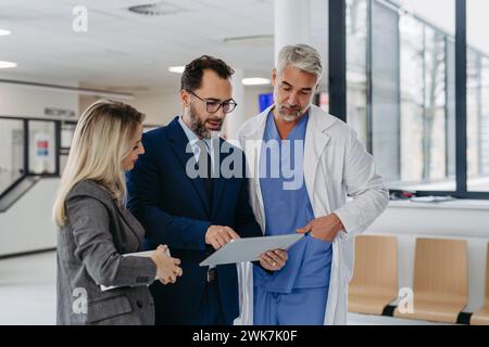 Pharmazeutischer Vertriebsmitarbeiter präsentiert Ärzten im medizinischen Gebäude neue Medikamente auf Tablette. Krankenhausleiter des Privatmediziners Stockfoto