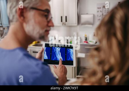 Arzt zeigt weiblichen Patienten MRT-Scan auf Tablette und bespricht Testergebnis in der Notaufnahme. Stockfoto