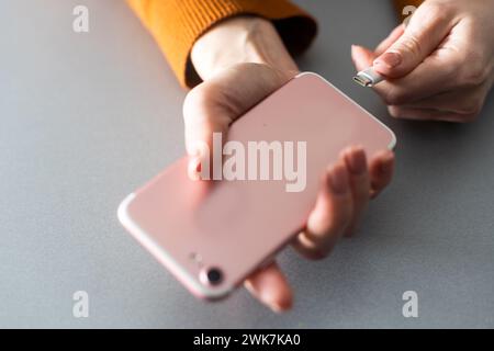 Frau Hände stecken ein Ladegerät in einem smart phone Stockfoto