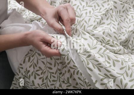 Die Frau schließt Knöpfe am Bettbezug, während sie das Bett macht Stockfoto