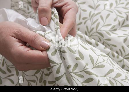 Die Frau schließt Knöpfe am Bettbezug, während sie das Bett macht Stockfoto