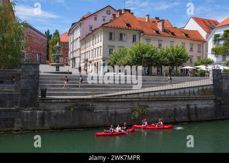 Ljubljana, Slowenien - 14. Juli 2022: Menschen in Kayaks auf dem Fluss Ljubljanica unterhalb des Ufers des Neuen Platzes (Novi Trg) im Stadtzentrum. Stockfoto