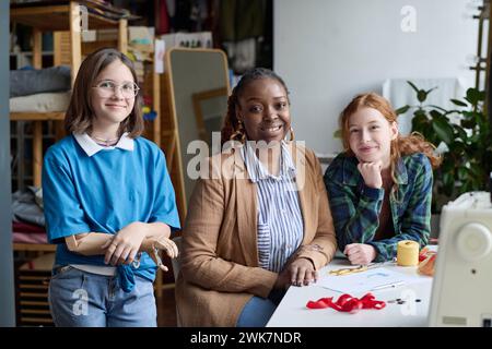 Porträt einer schwarzen erwachsenen Frau mit zwei Schülern, die in der Atelierwerkstatt in die Kamera schauen, Kopierraum Stockfoto